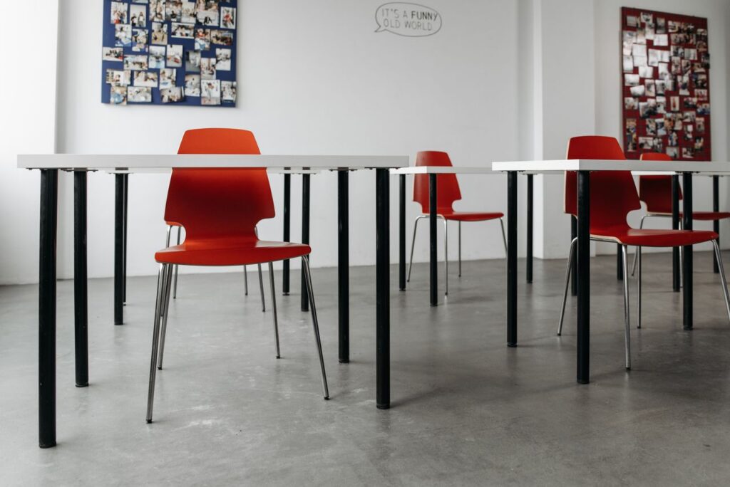 Contemporary classroom setup featuring red chairs and white tables, accentuated by photo collages on white walls.